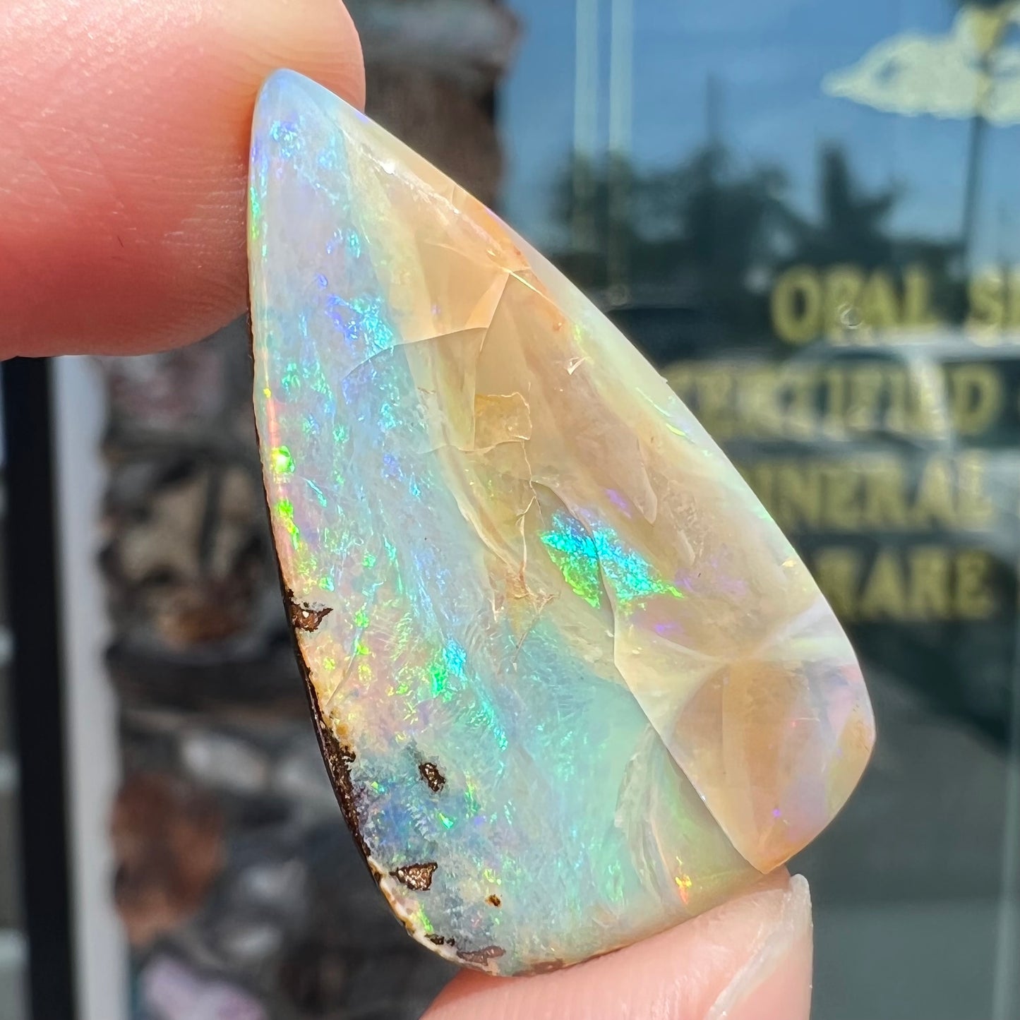A loose, pear shaped boulder opal stone from Queensland, Australia. Predominant colors are blue, purple, and green.
