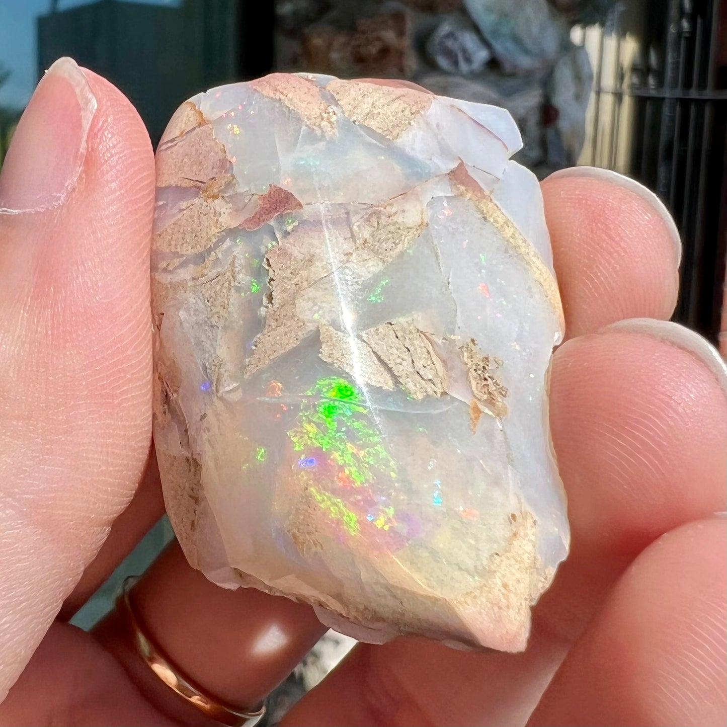 A preform polished matrix opal specimen from White Bluffs, Australia. Predominant colors are red, green, and violet.