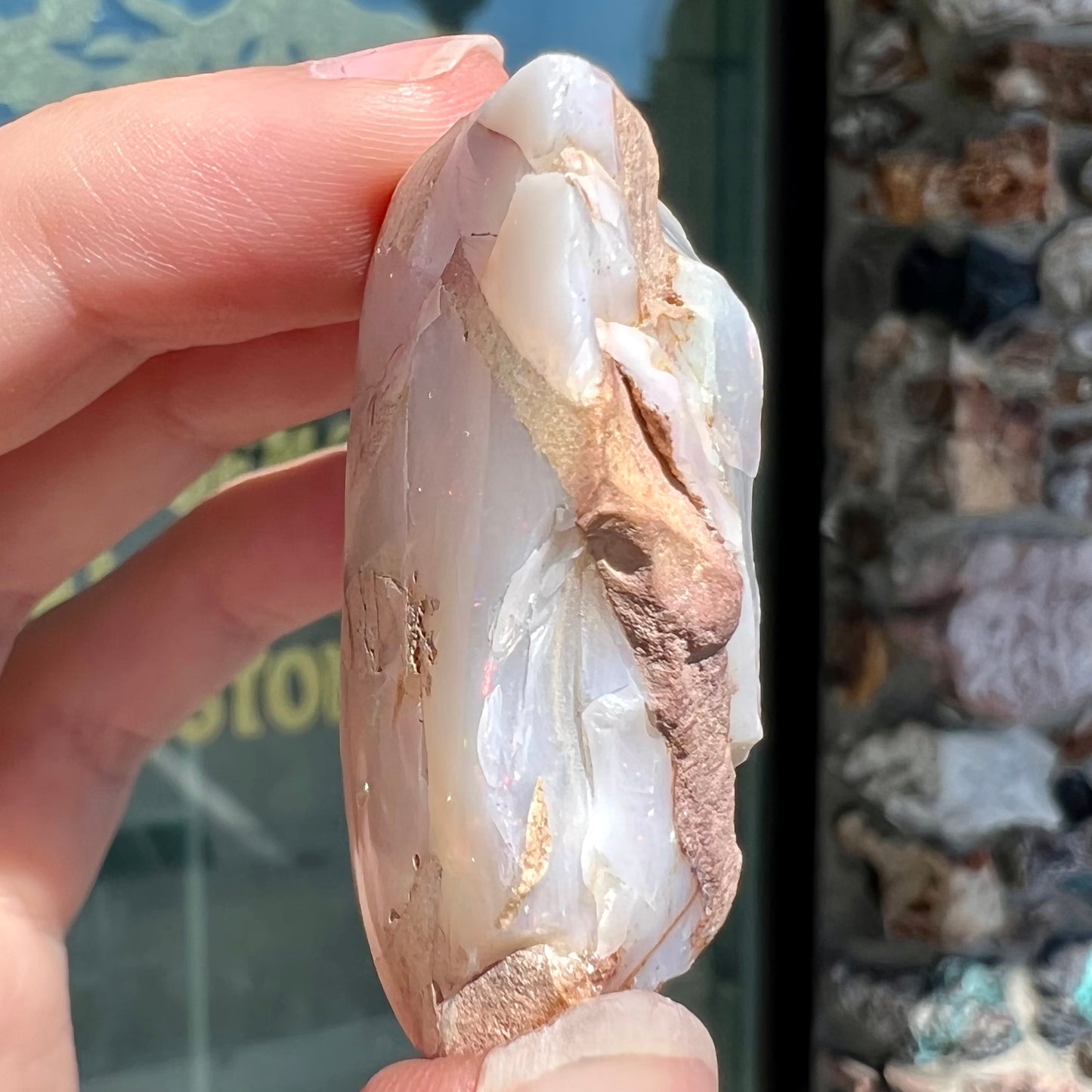 A preform polished matrix opal specimen from White Bluffs, Australia. Predominant colors are red, green, and violet.