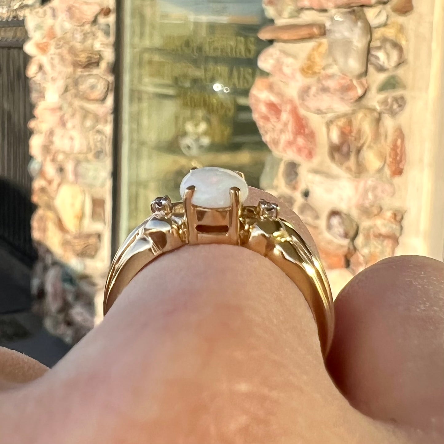A ladies' yellow gold white crystal opal and diamond ring. The opal is prong set.