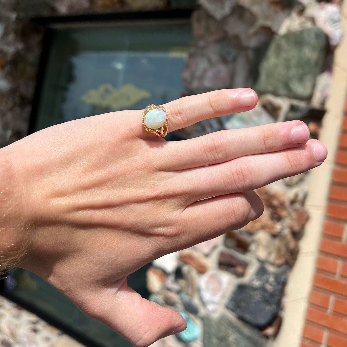A yellow gold solitaire engagement ring set with an oval cabochon cut white crystal opal.