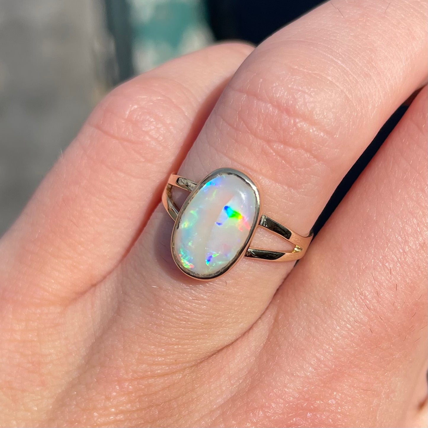 A handmade split shank white opal solitaire ring in yellow gold.