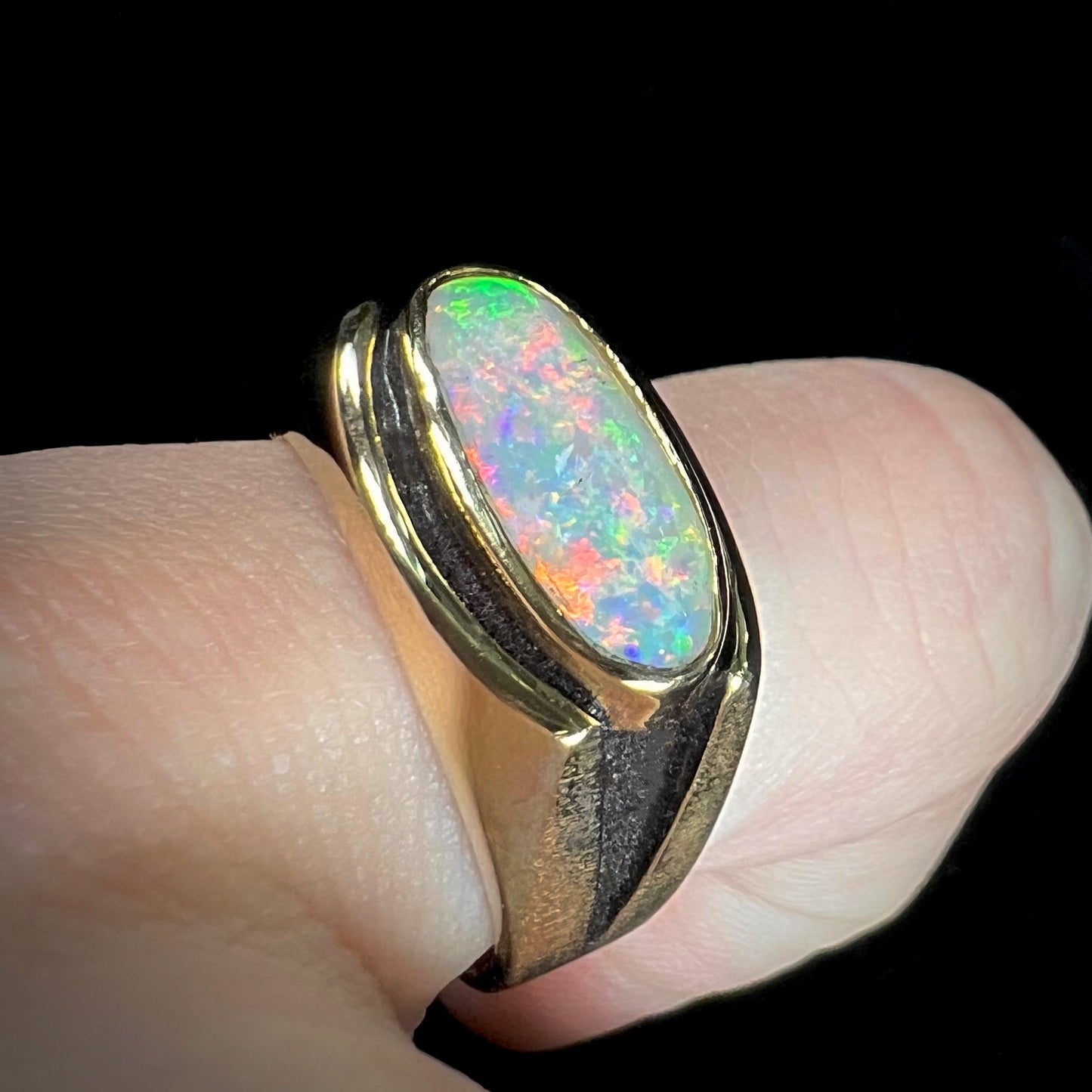 An Australian white crystal opal men's ring in solid yellow gold. The recesses of the ring have been blackened.