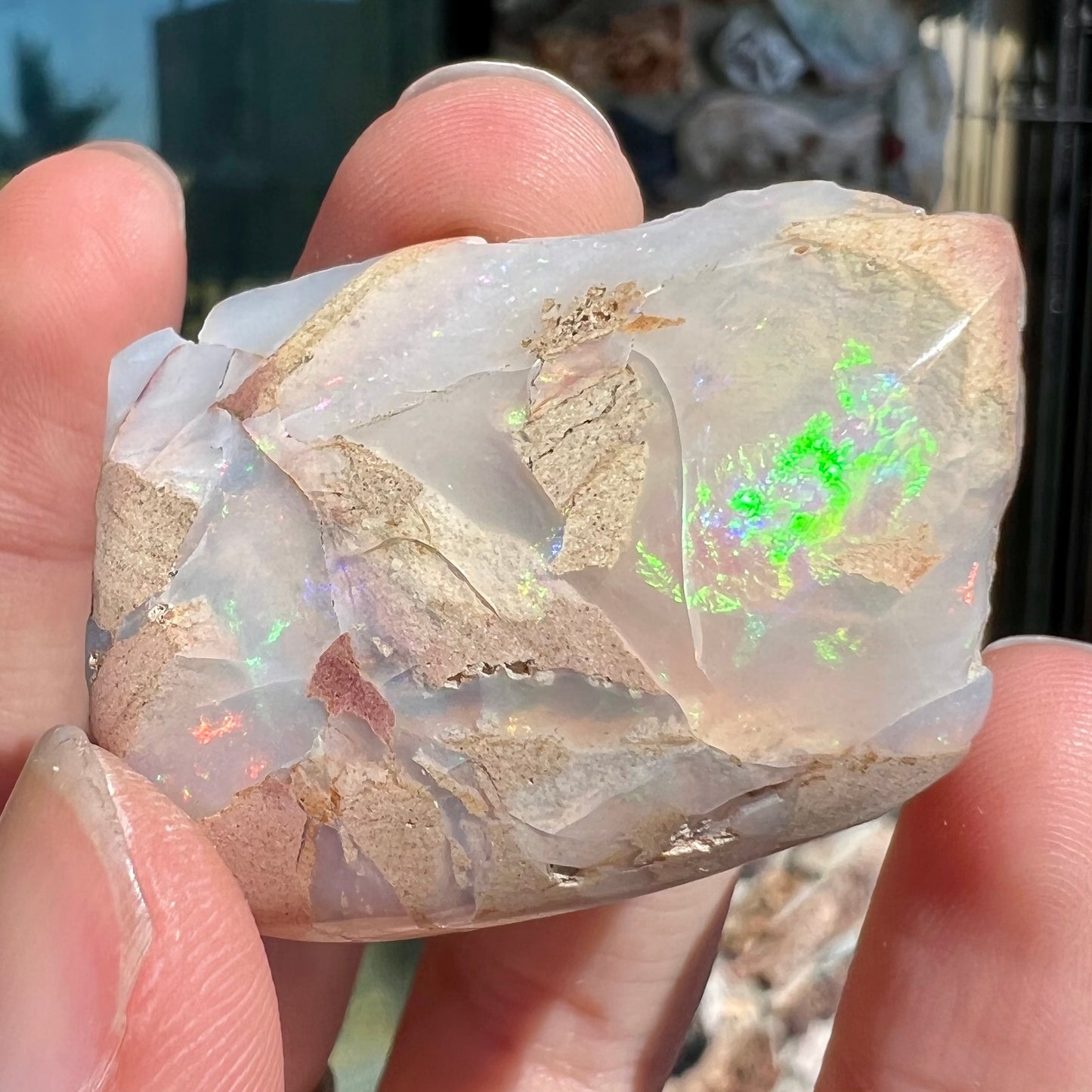 A preform polished matrix opal specimen from White Bluffs, Australia. Predominant colors are red, green, and violet.