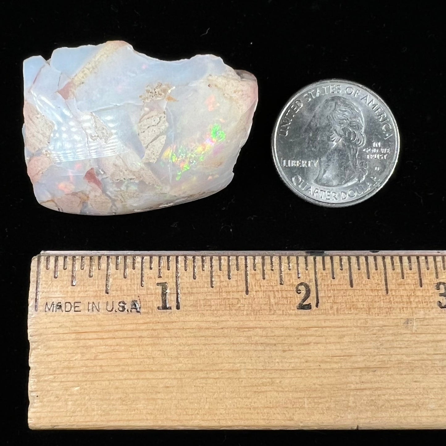 A preform polished matrix opal specimen from White Bluffs, Australia. Predominant colors are red, green, and violet.