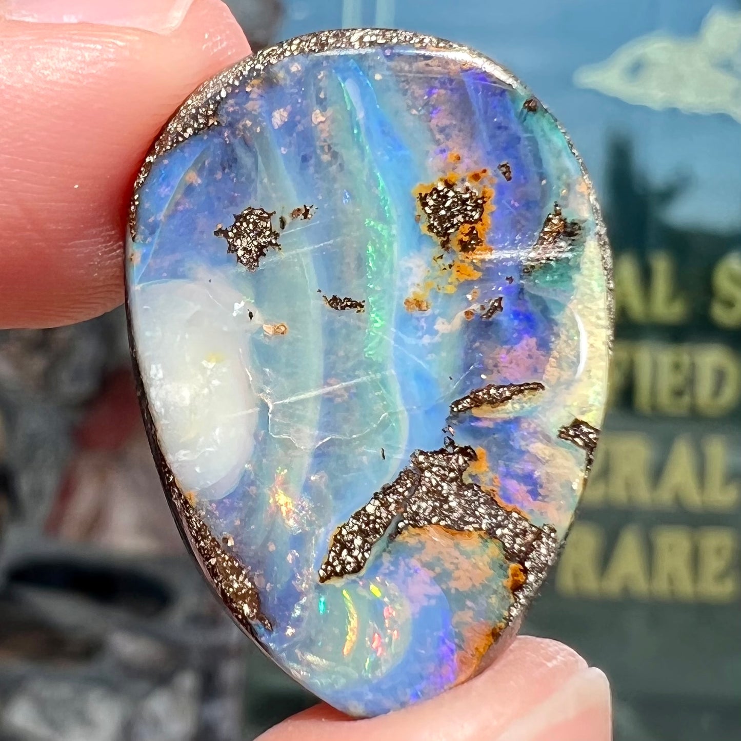 A loose, pear shaped Australian boulder opal. The pattern on the opal resembles the face of a very sad man.