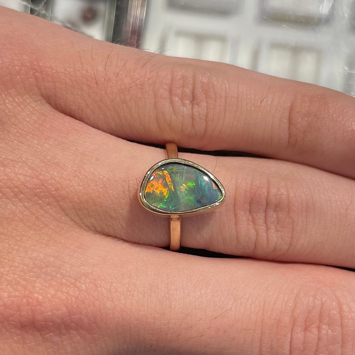 A freeform cut semi-black opal from Lightning Ridge, Australia set in a bezel set yellow gold solitaire ring.