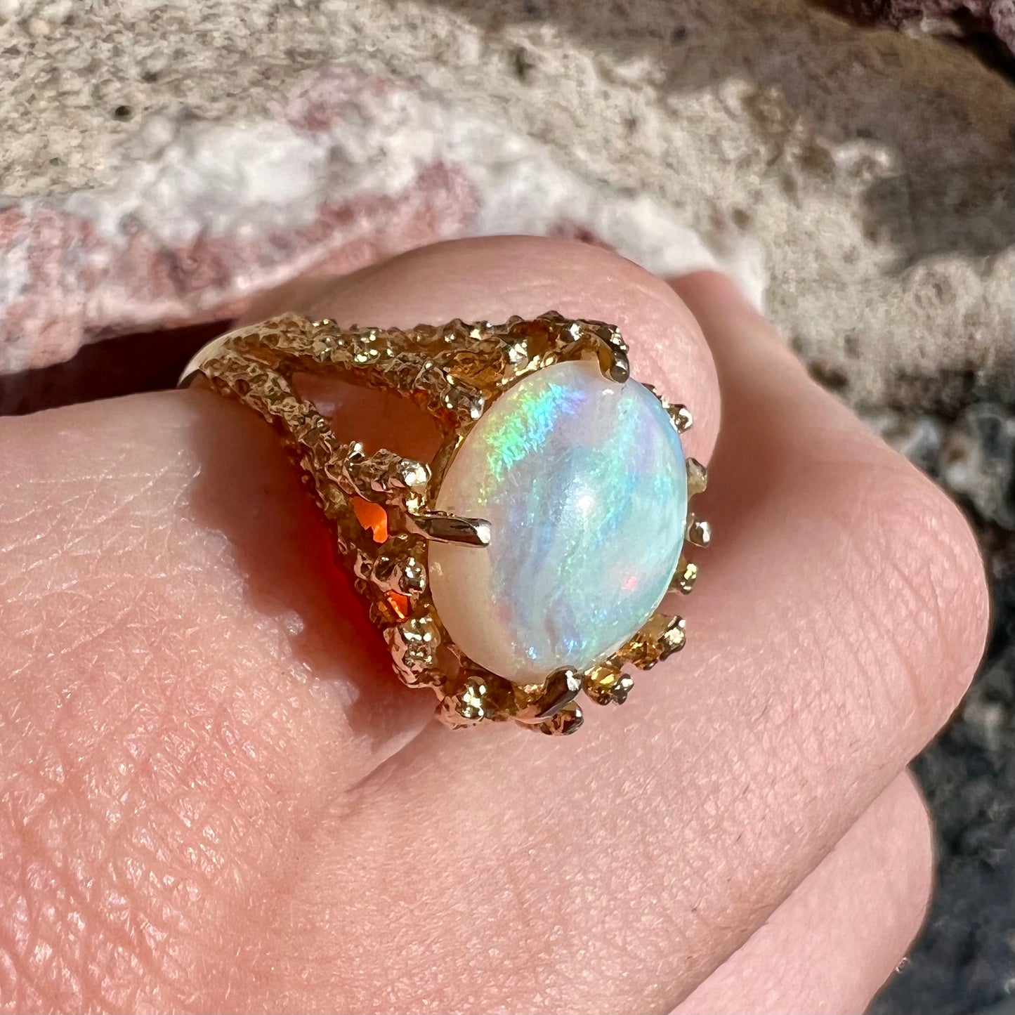 A yellow gold solitaire engagement ring set with an oval cabochon cut white crystal opal.
