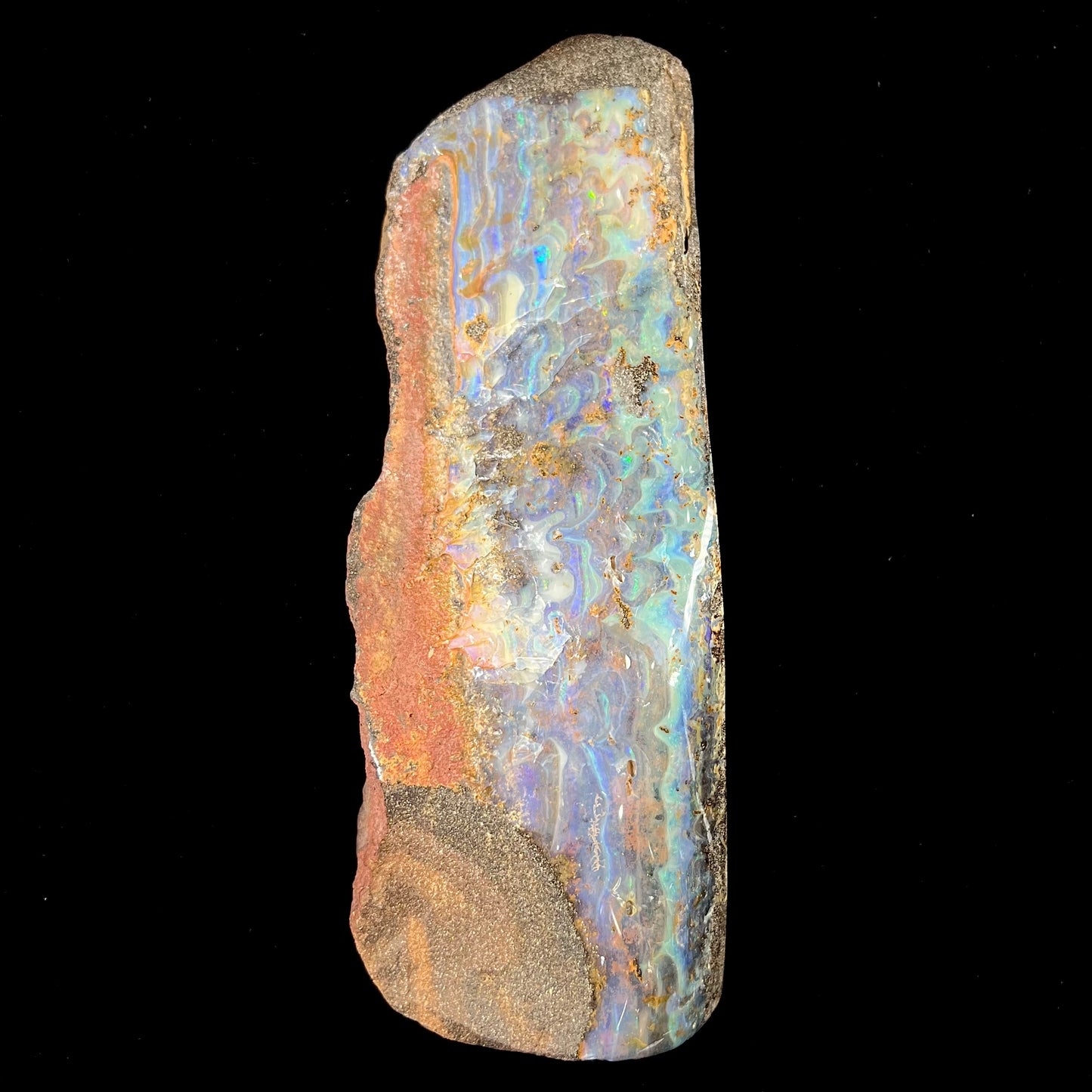 A 7 inch long, polished Quilpie boulder opal specimen. The stone shows colors of blue, green, and orange.