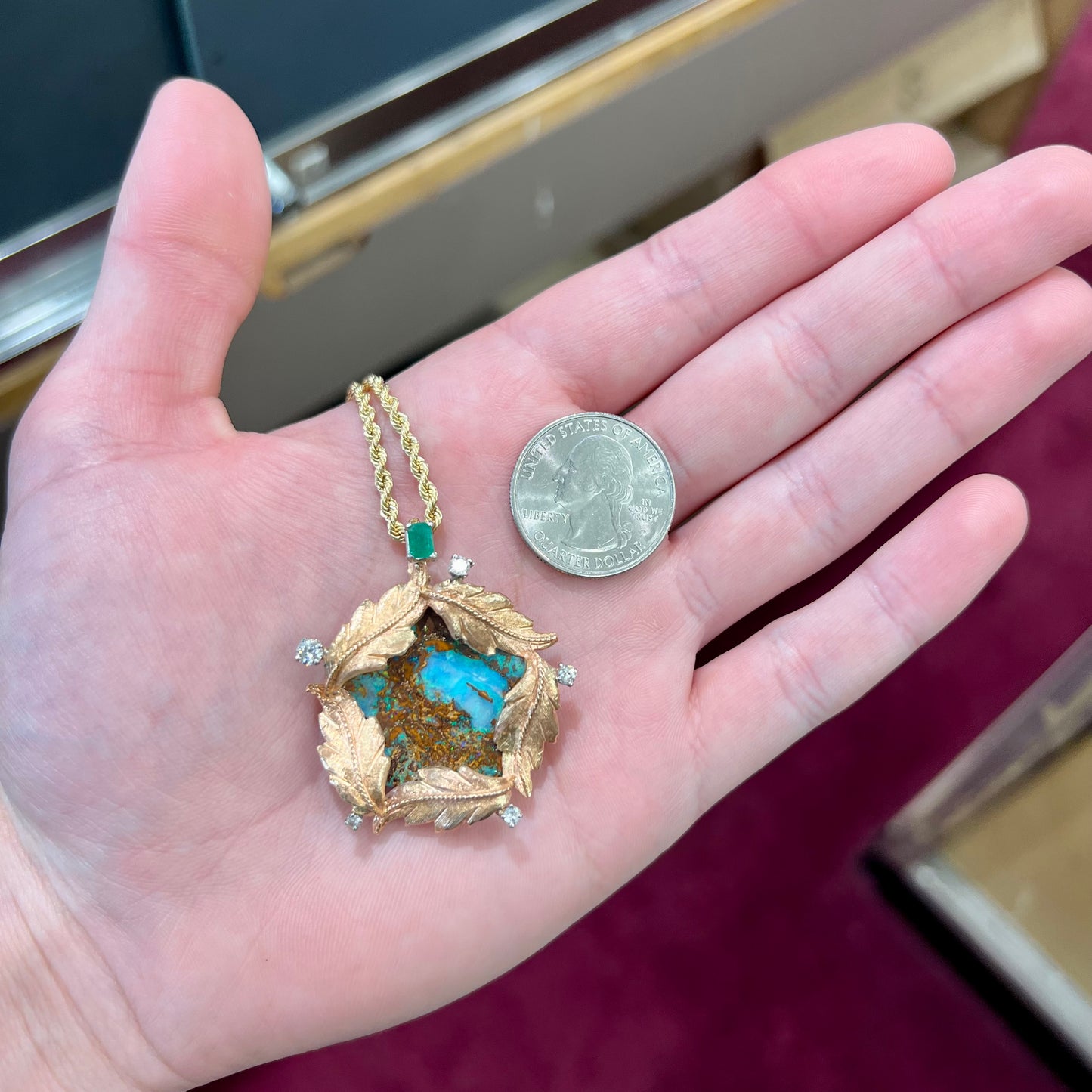 A gold opalized wood, diamond, and emerald pendant. The opal is set in a wreath of gold feathers that form a star.