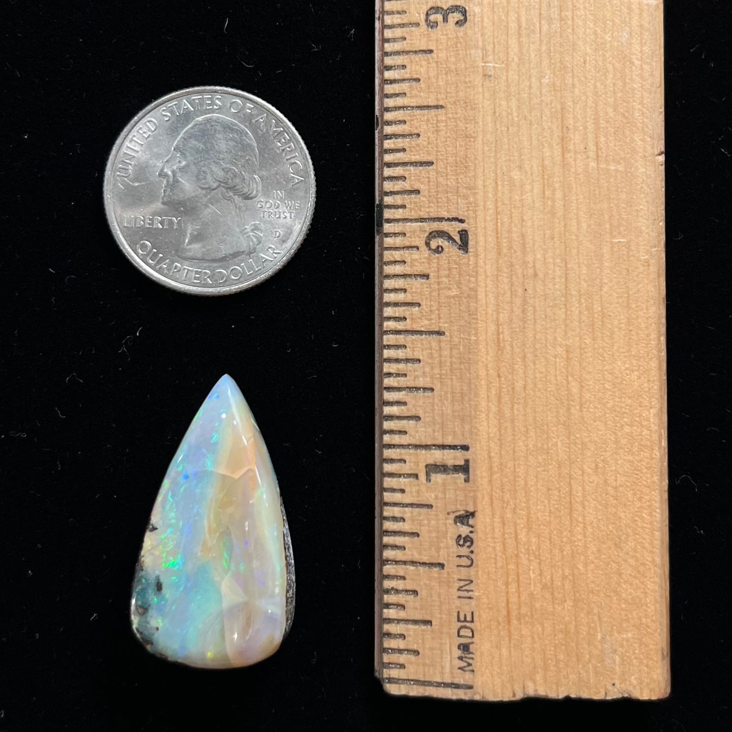 A loose, pear shaped boulder opal stone from Queensland, Australia. Predominant colors are blue, purple, and green.