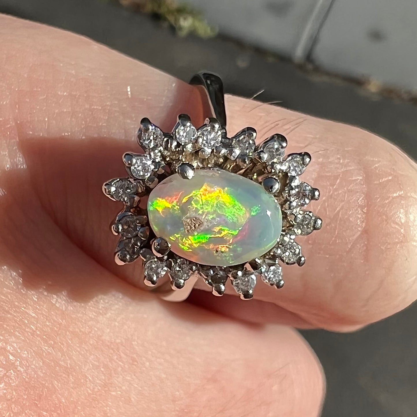 A white crystal opal ring cast in white gold with a halo of round cut diamonds.