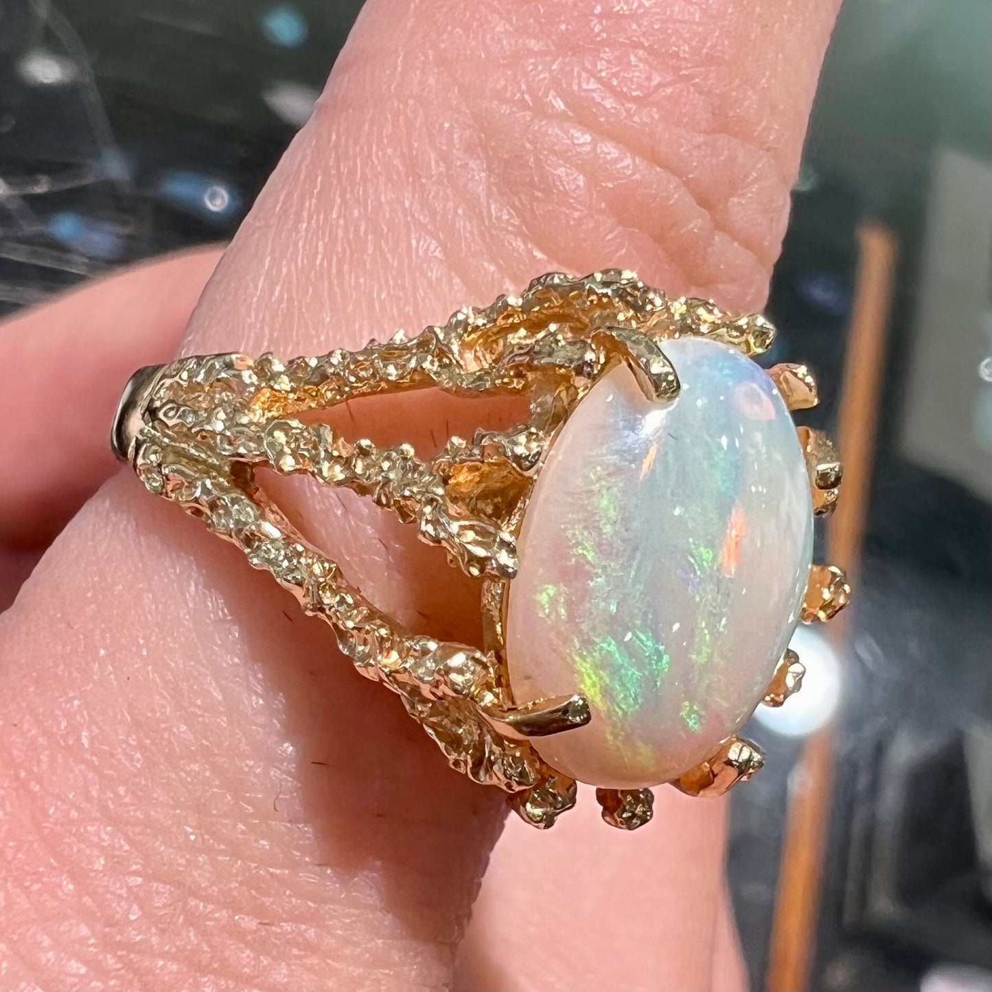 A yellow gold solitaire engagement ring set with an oval cabochon cut white crystal opal.