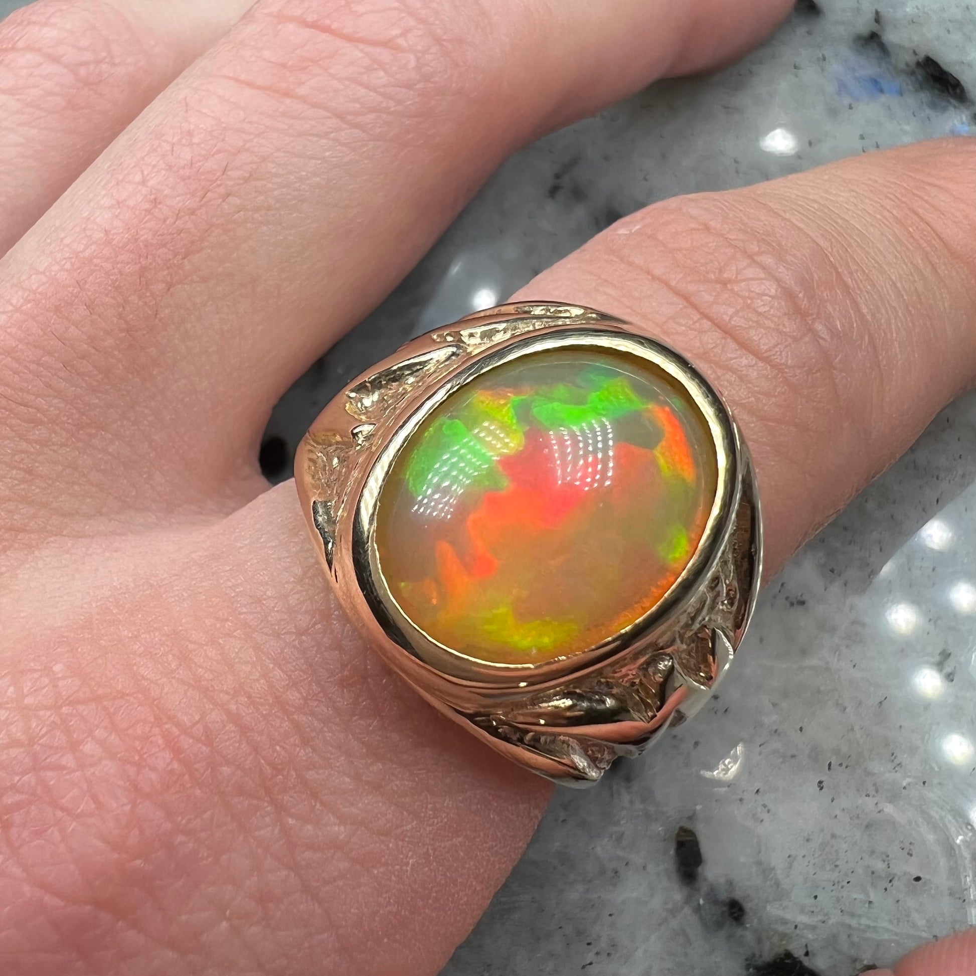 A solid yellow gold solitaire men's fire opal ring.  The stone is an orange oval cabochon cut.