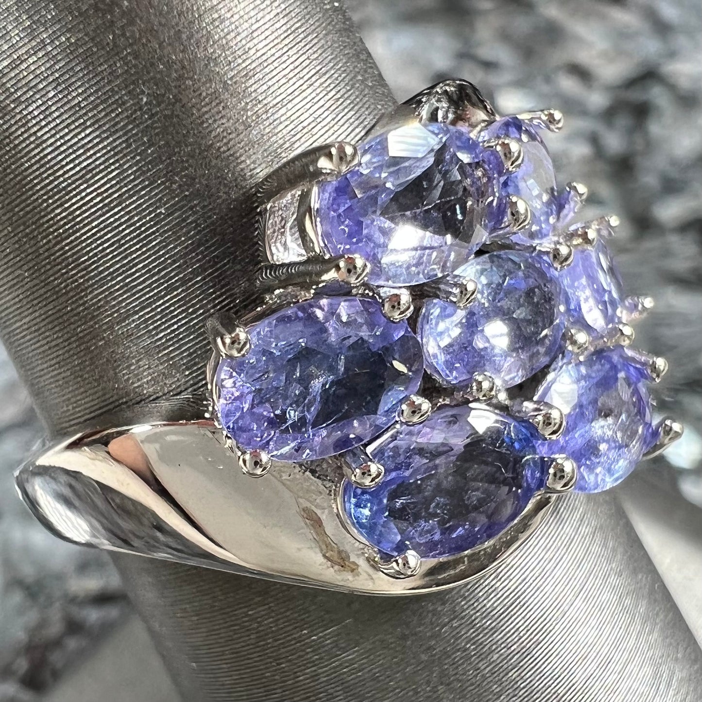 A sterling silver cluster ring prong set with seven faceted oval cut blue tanzanite stones.
