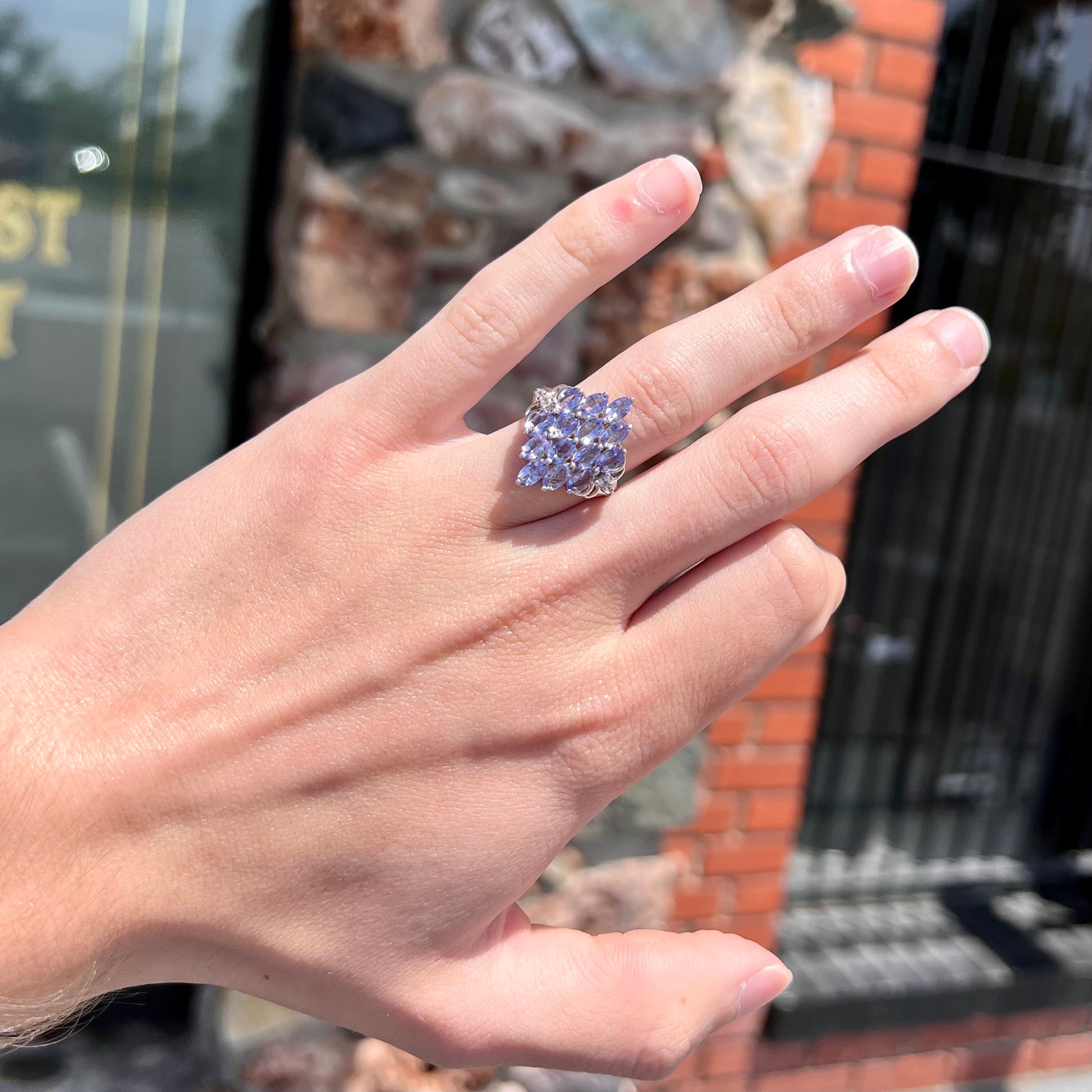A sterling silver gemstone cluster ring set with oval cut tanzanite stones and round cubic zirconia accents.