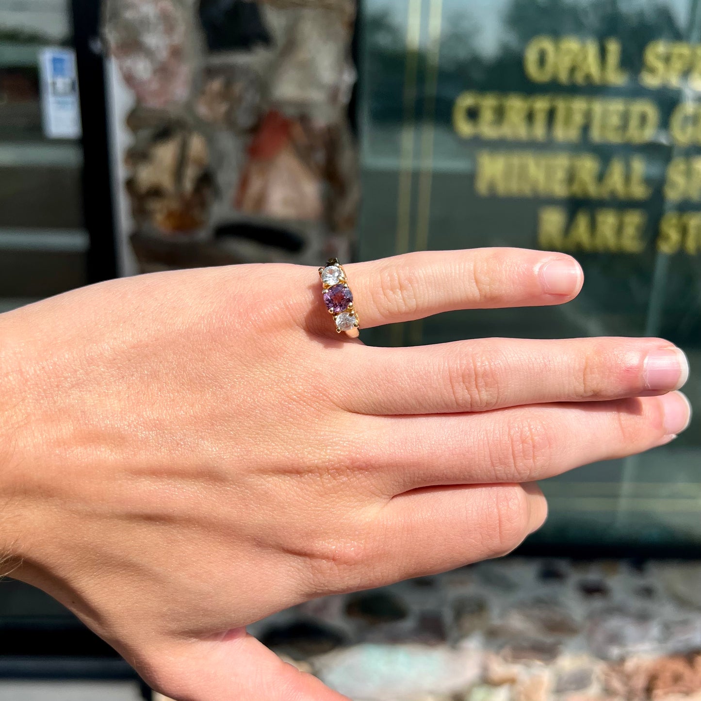 A yellow gold three stone ring set with two round cut white zircons and one cushion cut purple spinel.