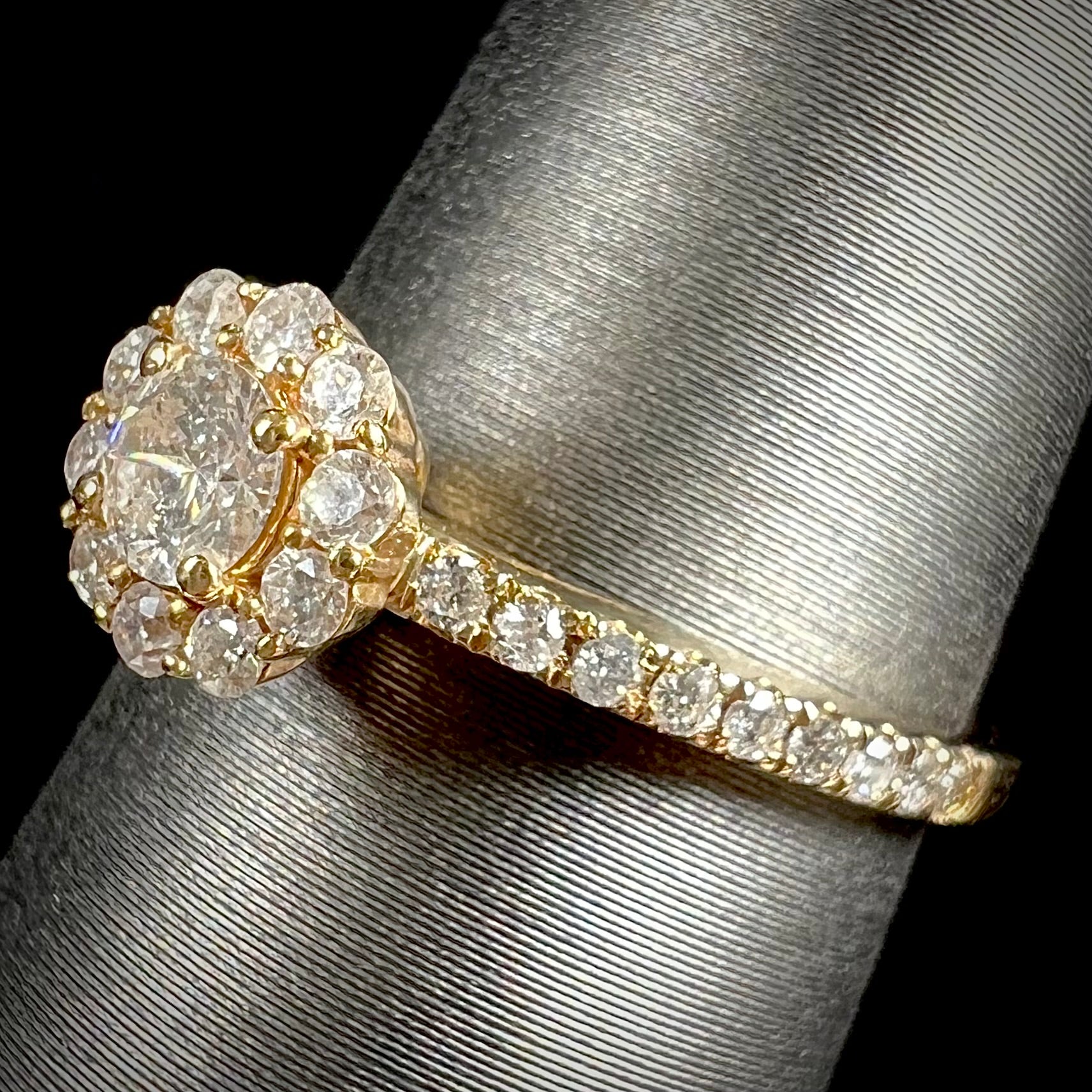 A ladies' diamond halo engagement ring cast in yellow gold.  The center stone is a 0.19ct round cut natural diamond.
