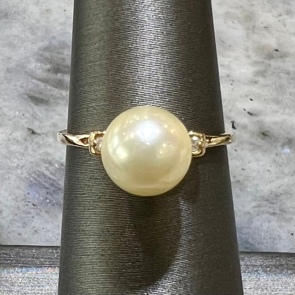 A simple, vintage, yellow gold pearl ring set with two side diamonds.