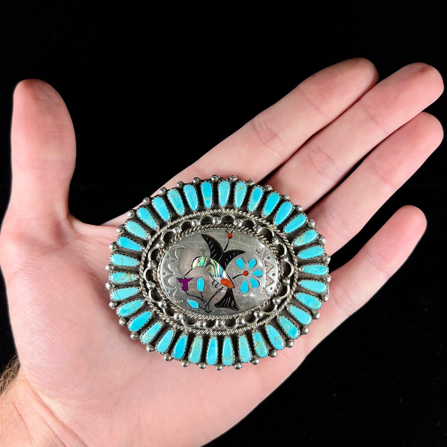 A unisex sterling silver belt buckle featuring the motif of a stone inlaid hummingbird set with petit point turquoise accents, handmade by Navajo artist, Leo G. Harvey.