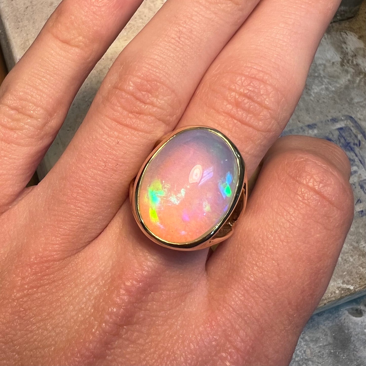 A gold split shank solitaire ring set with an oval cabochon cut 16.83 carat Ethiopian jelly fire opal.