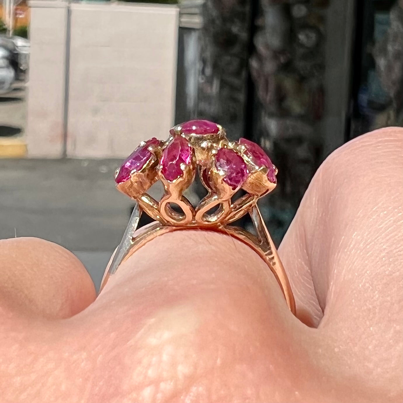 A yellow gold pink Burma ruby cluster ring with a faceted oval center stone surrounded by marquise cut stones.