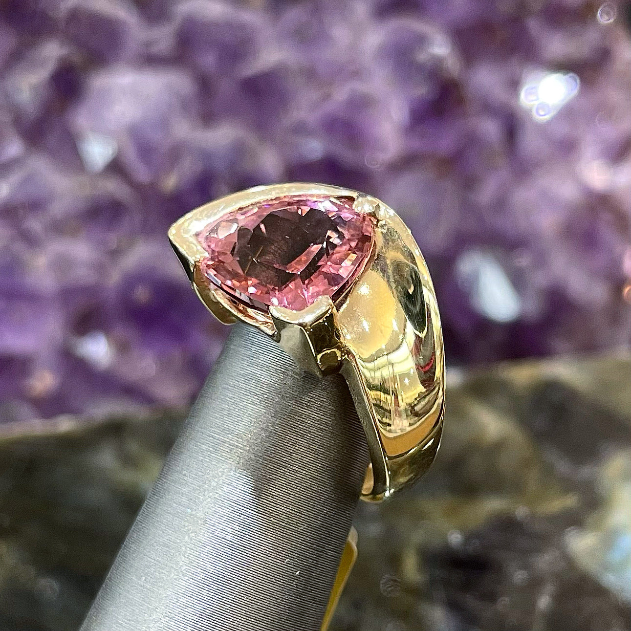 A unisex trillion cut pink tourmaline ring half bezel set in 14k yellow gold.