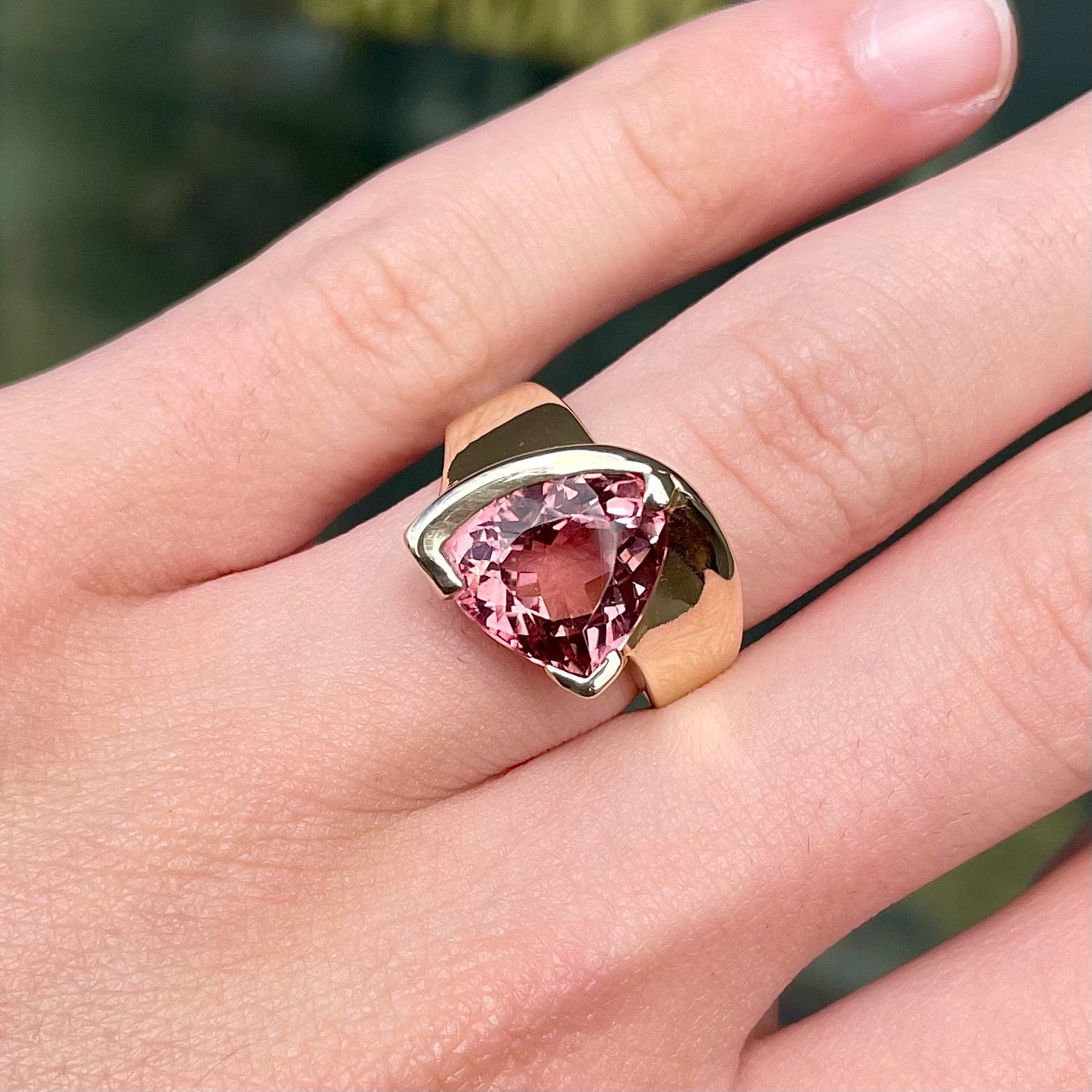 A unisex trillion cut pink tourmaline ring half bezel set in 14k yellow gold.