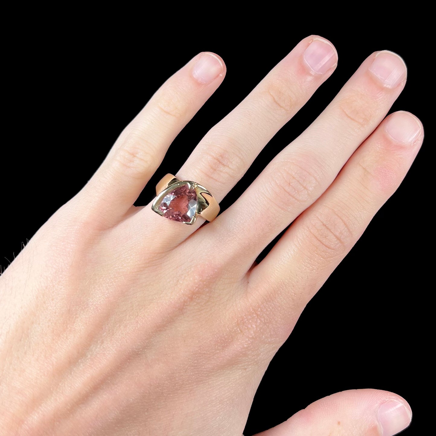 A unisex, yellow gold, trillion cut pink tourmaline solitaire ring.