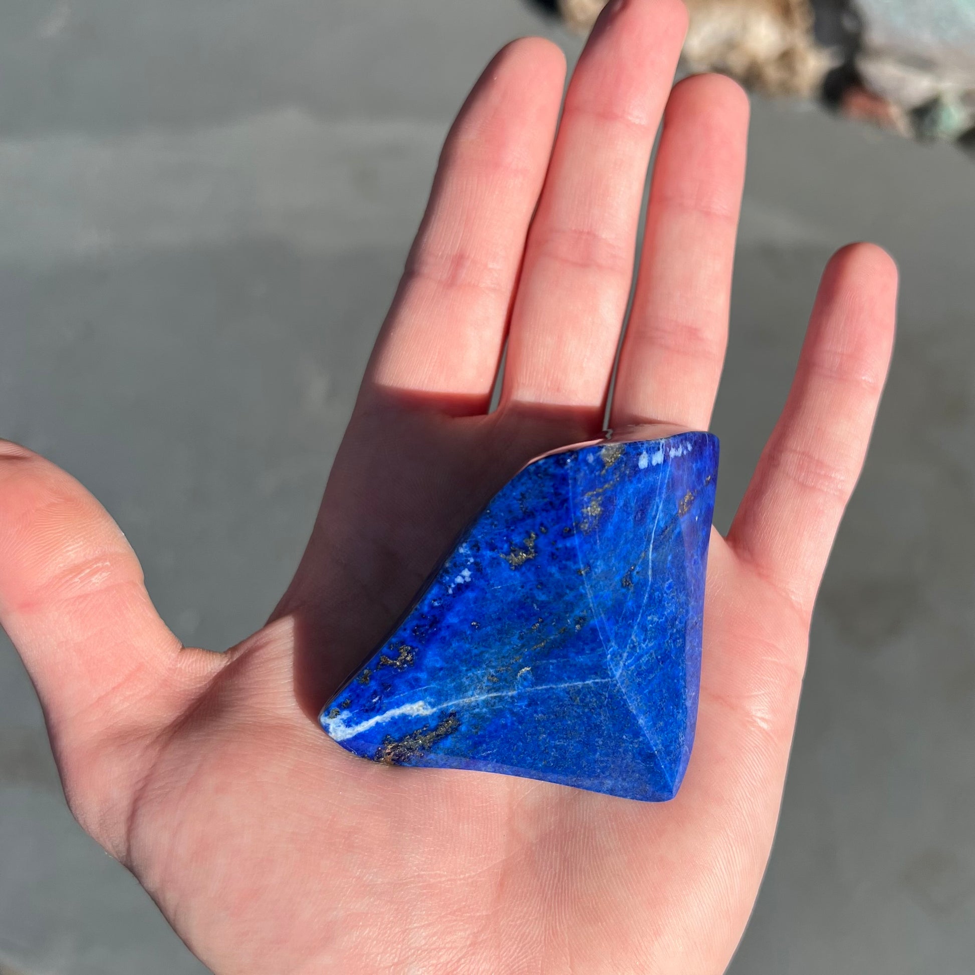 A loose polished sculpture made from royal blue lapis lazuli with golden pyrite inclusions.