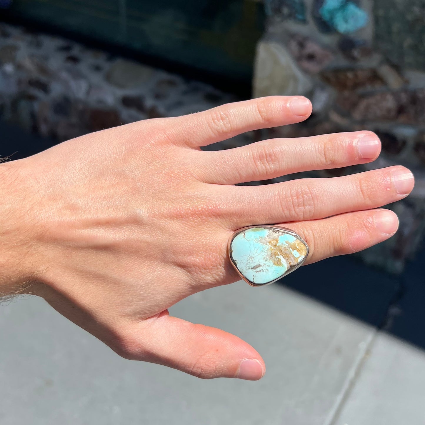 A men's sterling silver ring set with a powder blue turquoise stone. The ring is rustic style.