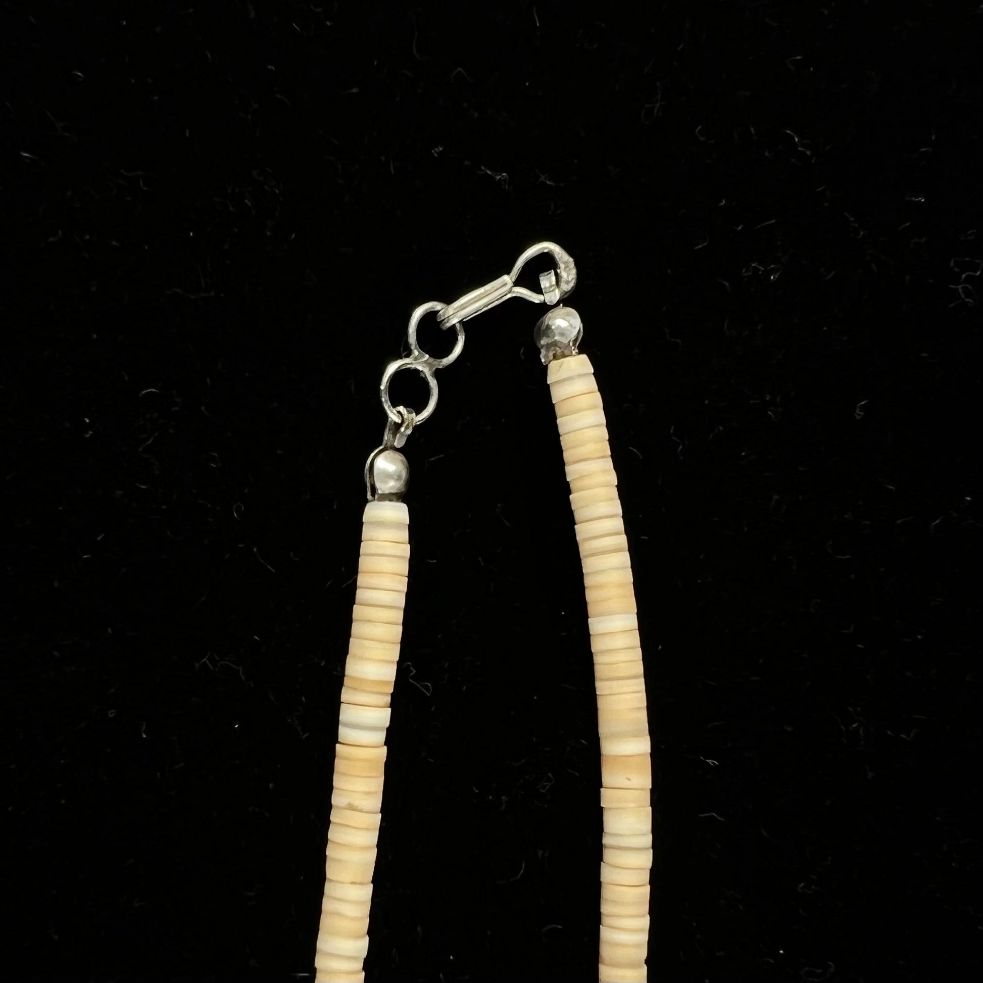 A three dimensional mosaic stone inlay pendant set with turquoise, lapis lazuli, coral, and mother of pearl on a puka shell necklace.