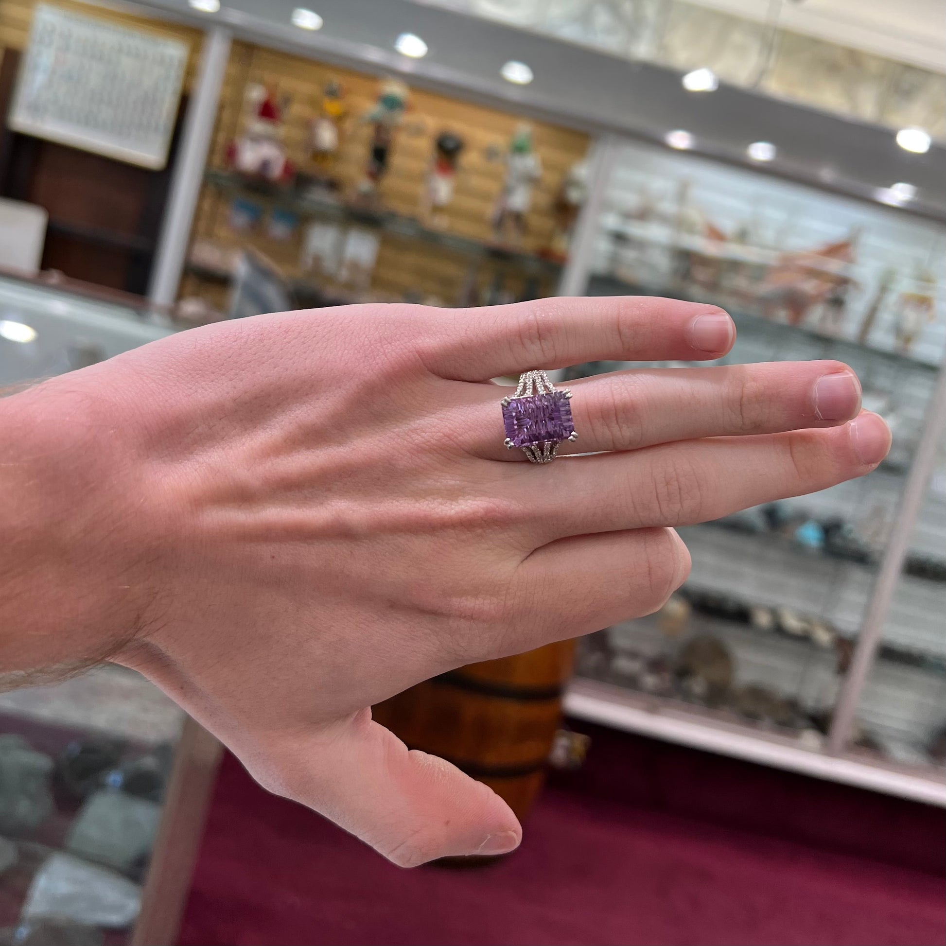 A white gold ladies ring set with an emerald laser cut amethyst and diamond chip accents.