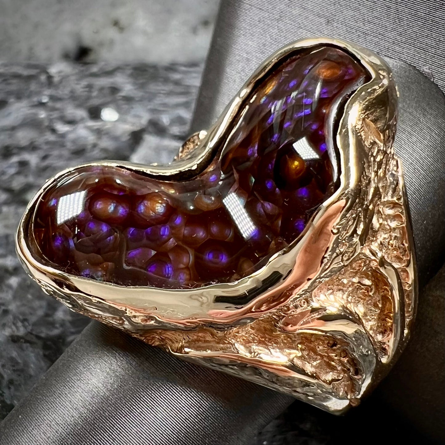 A men's Deer Creek fire agate solitaire ring cast in yellow gold. The stone is predominantly purple.