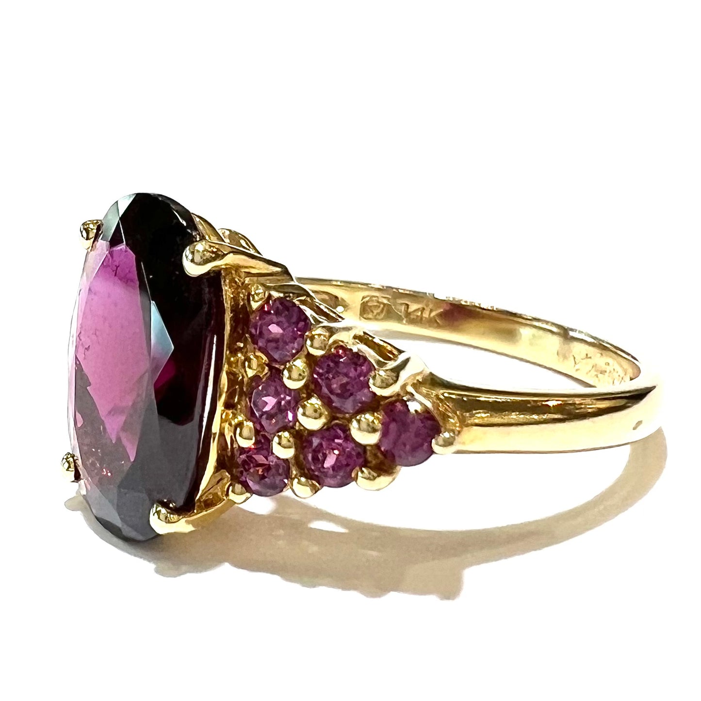A yellow gold ring with purple prong set rhodolite garnets. The shank is stamped with "14K."