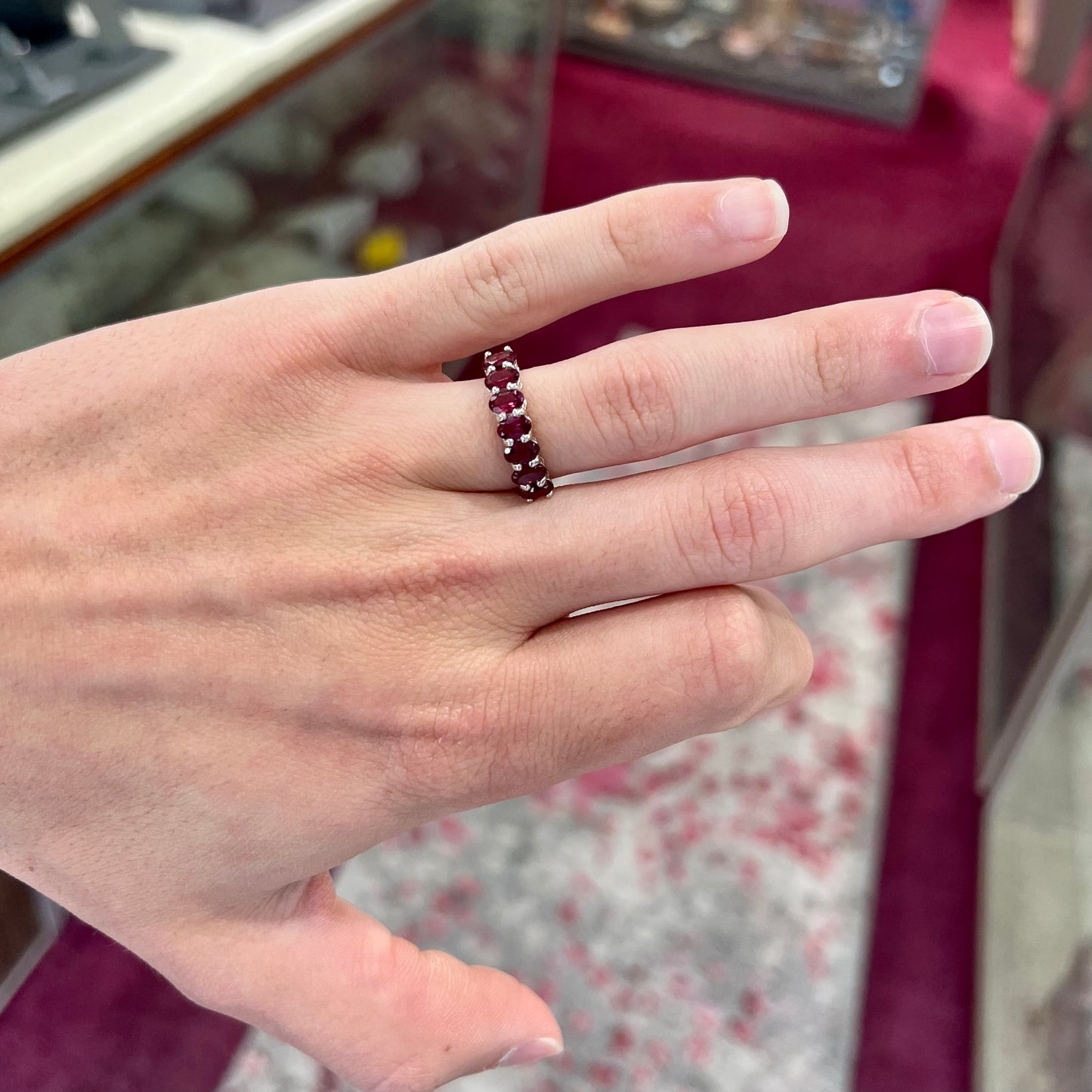 A sterling silver band set with 7 oval cut, purple rhodolite garnet stones.