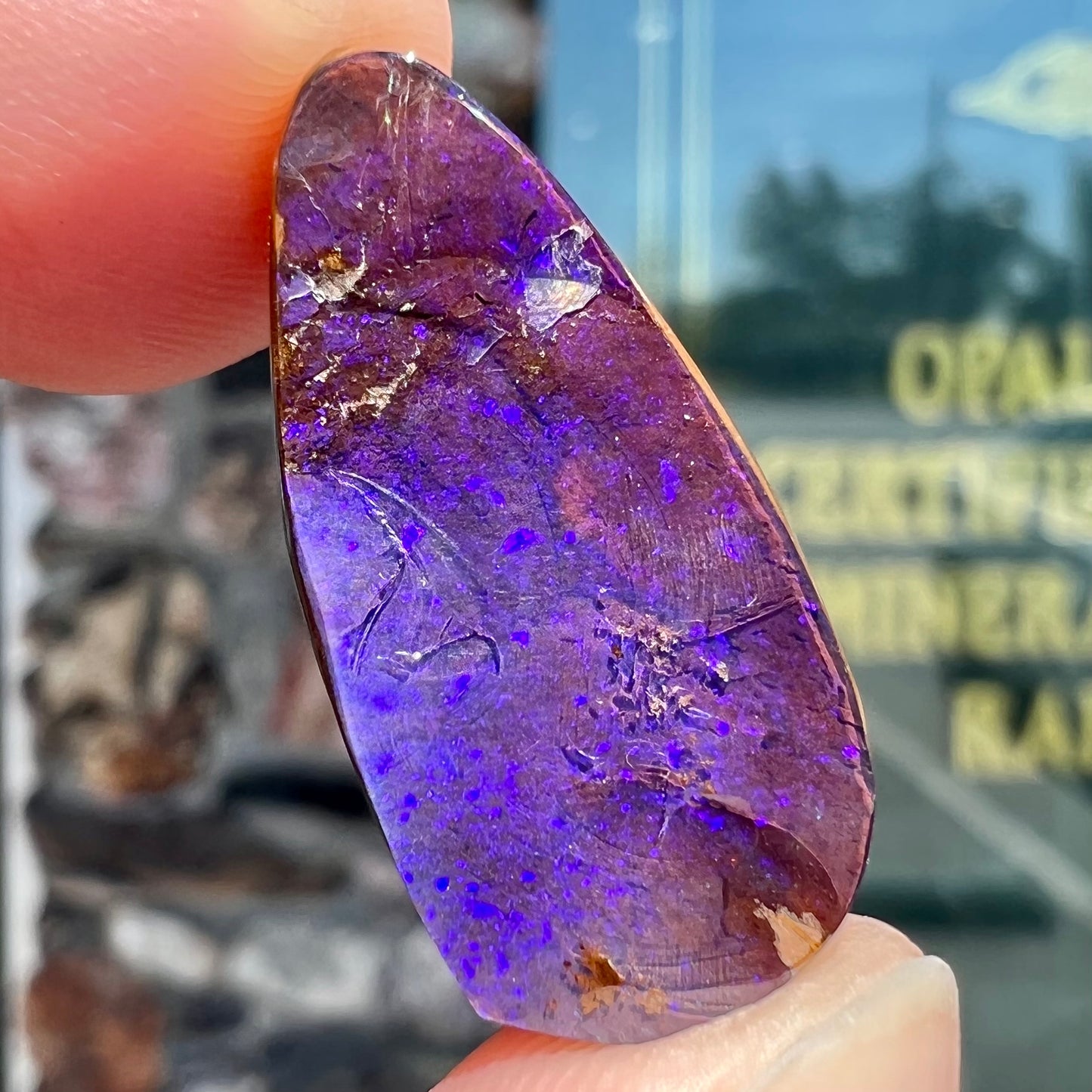A loose, teardrop shaped purple boulder opal stone.