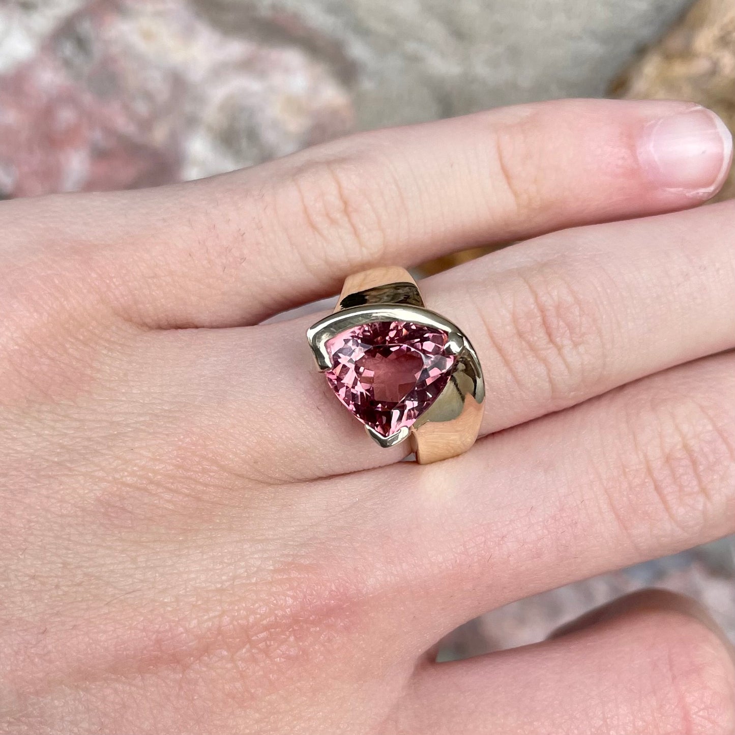 A unisex trillion cut pink tourmaline ring half bezel set in 14k yellow gold.