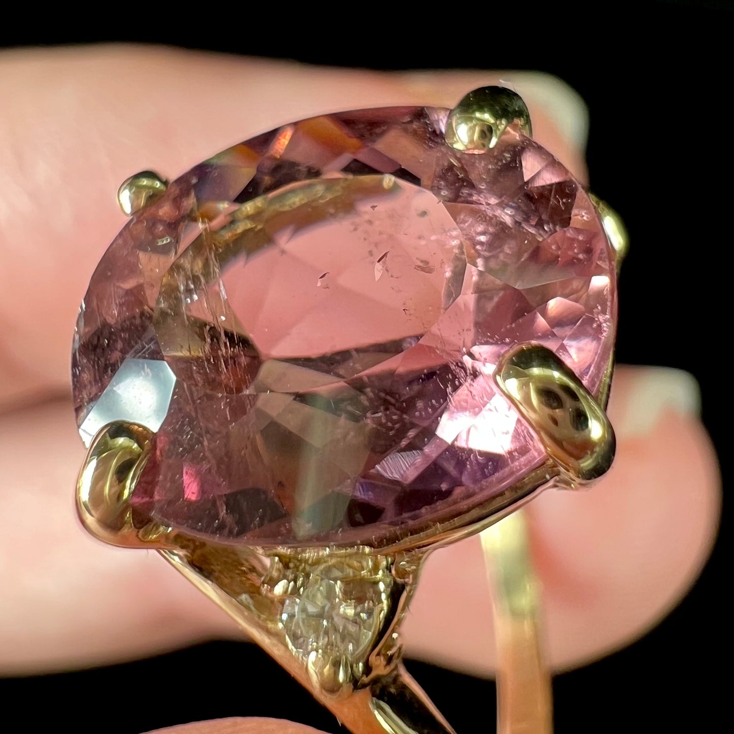 A ladies' yellow gold, faceted oval cut purple tourmaline ring set with diamond accents.