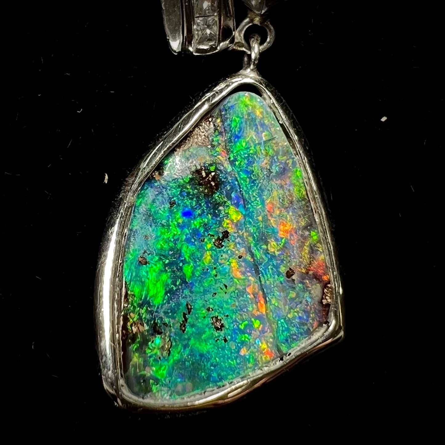 A white gold necklace set with diamonds and a dangling, bezel set boulder opal.