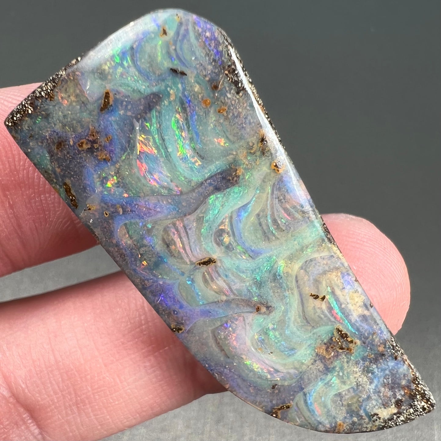 A loose, freeform cut, natural boulder opal stone from Quilpie, Australia.