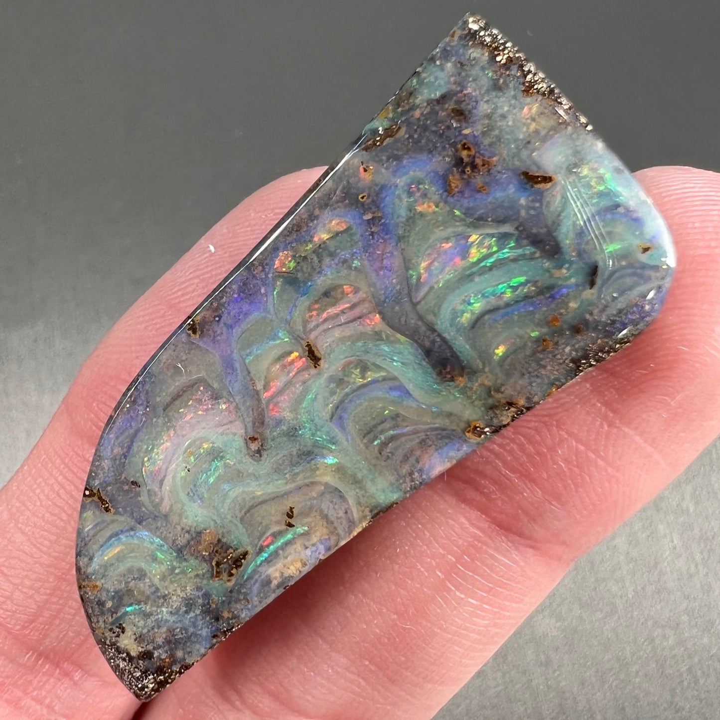 A loose, freeform cut, natural boulder opal stone from Quilpie, Australia.