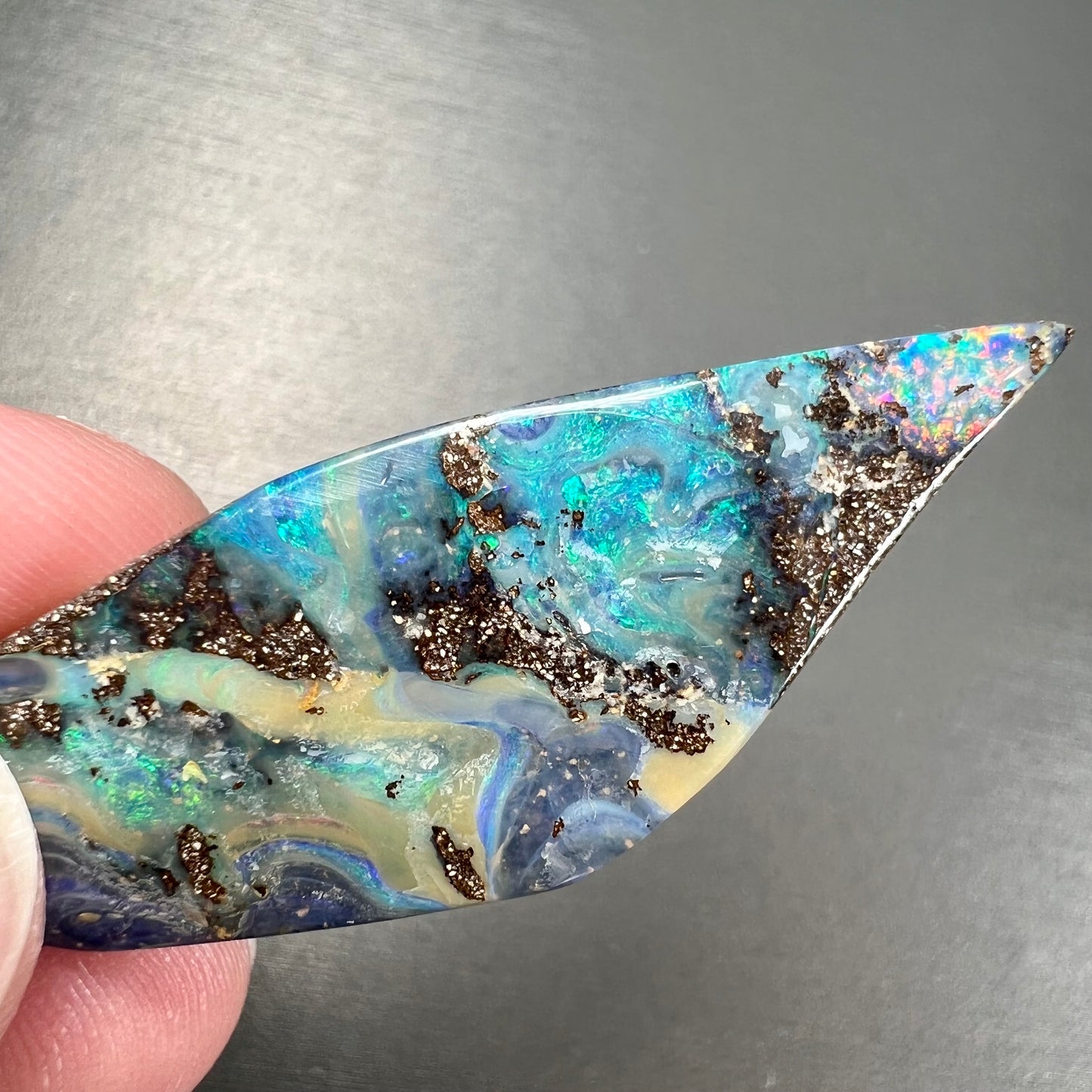 A loose Quilpie boulder opal stone. The stone is blue and has a bright rainbow tip.
