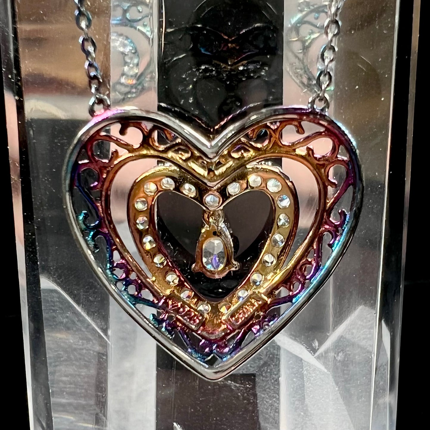 A sterling silver and cubic zirconia heart necklace. The silver has a rainbow patina.