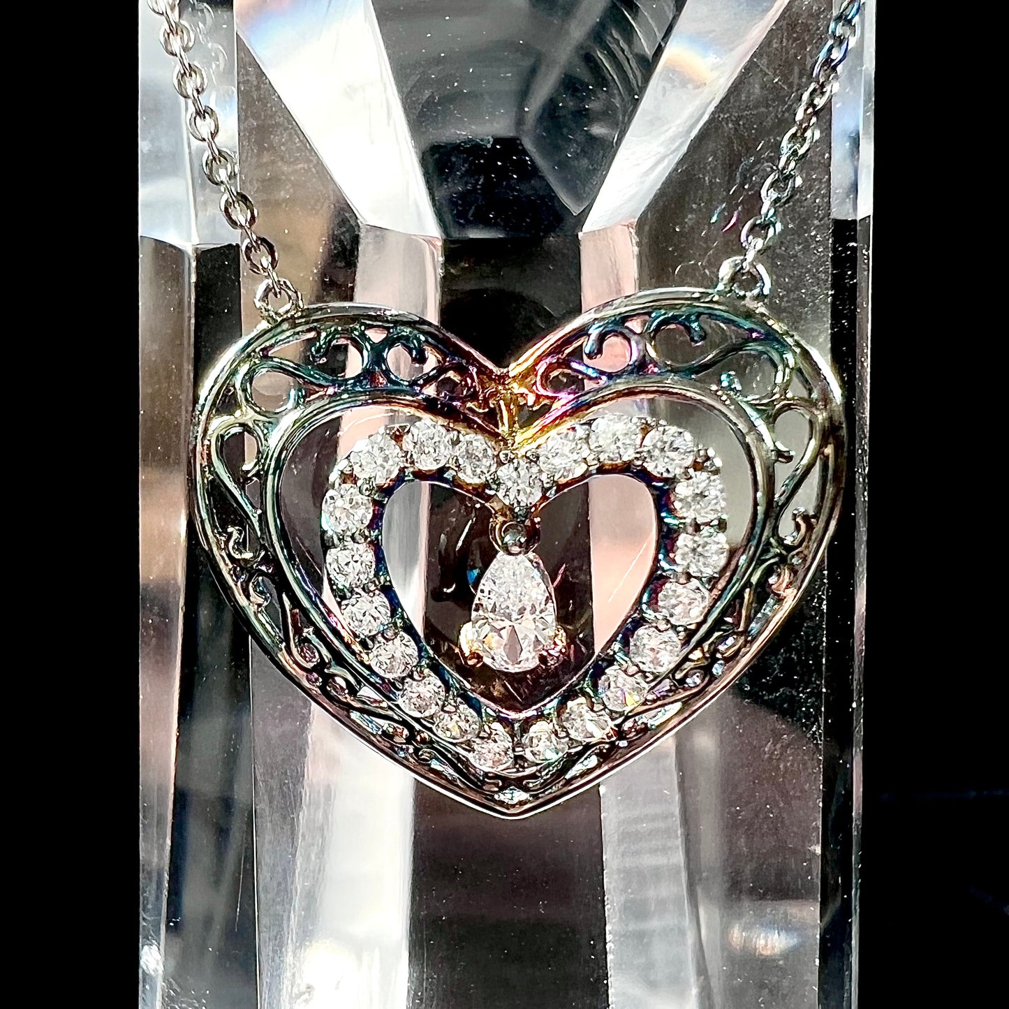 A sterling silver and cubic zirconia heart necklace. The silver has a rainbow patina.