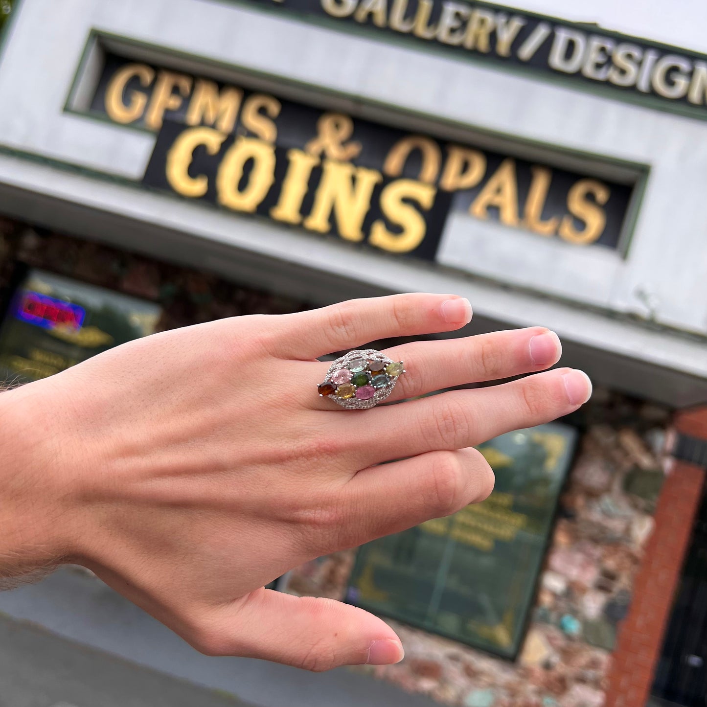 A silver gemstone cluster ring set with a rainbow of multicolored tourmaline stones.