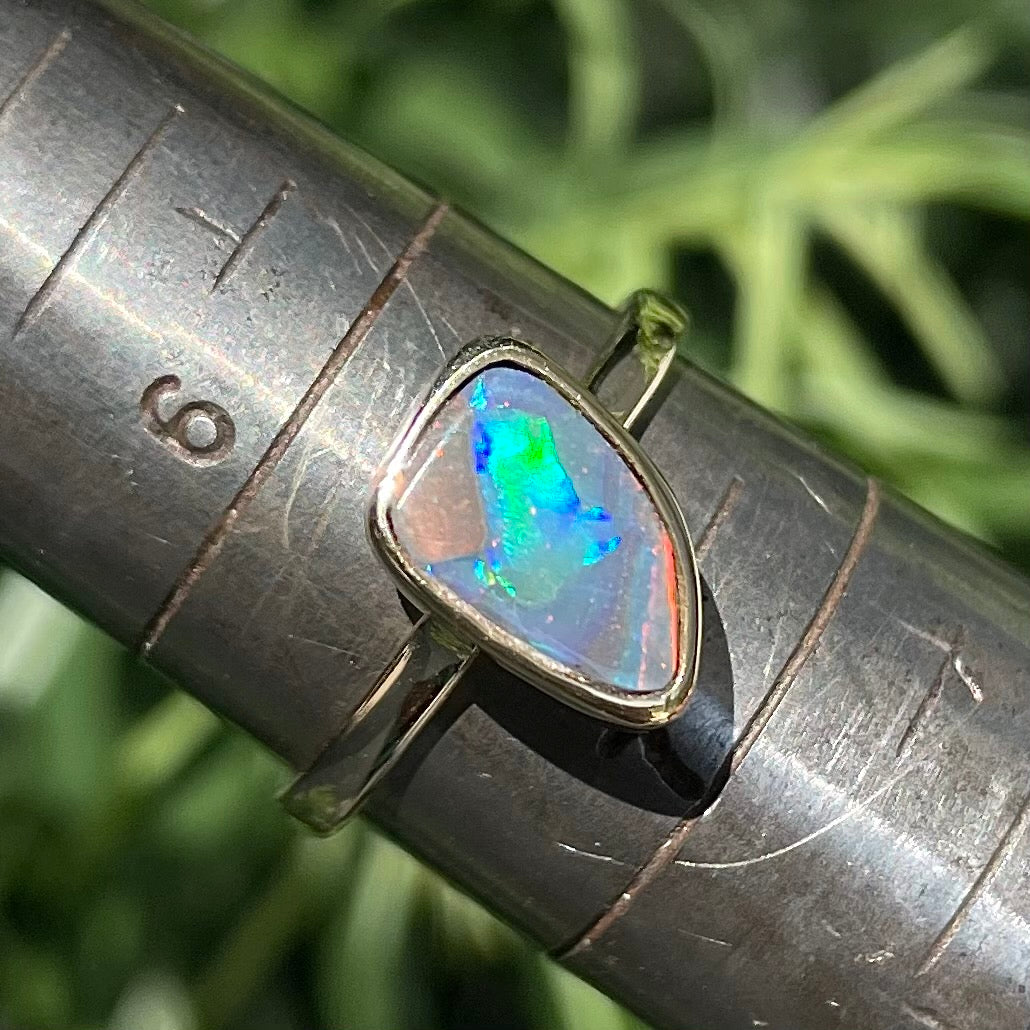 A handmade yellow gold solitaire ring bezel set with a Lightning Ridge red-on-black harlequin opal.