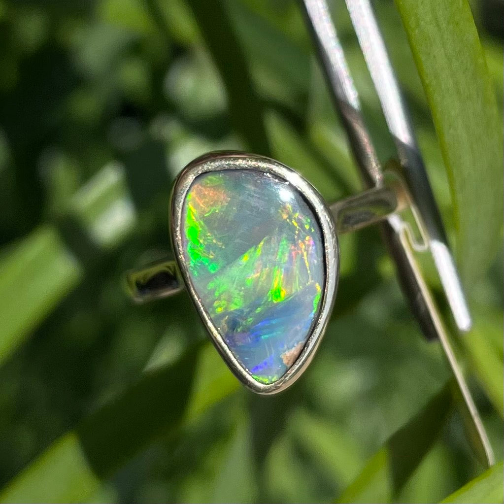 A freeform cut semi-black opal from Lightning Ridge, Australia set in a bezel set yellow gold solitaire ring.