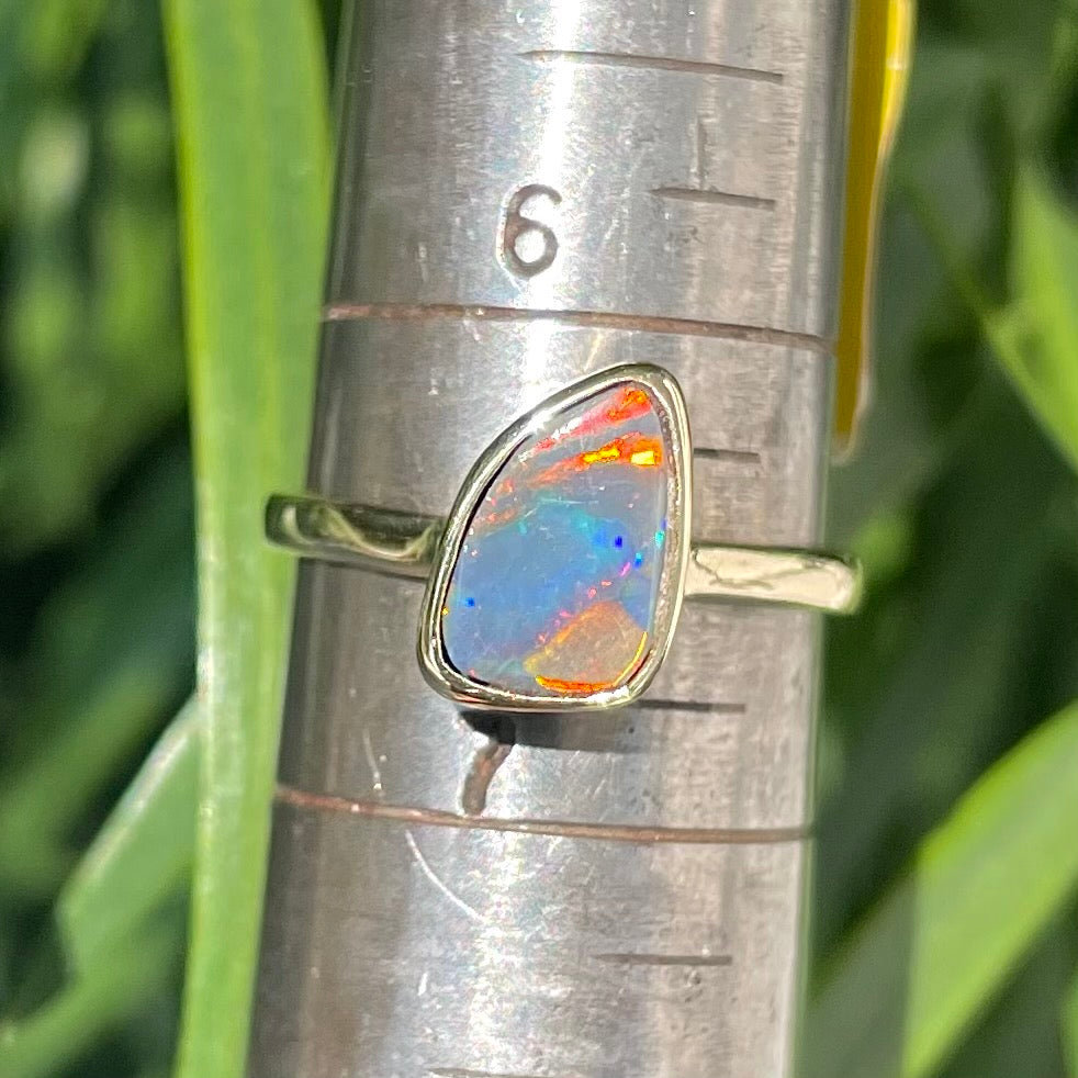 A handmade yellow gold solitaire ring bezel set with a Lightning Ridge red-on-black harlequin opal.