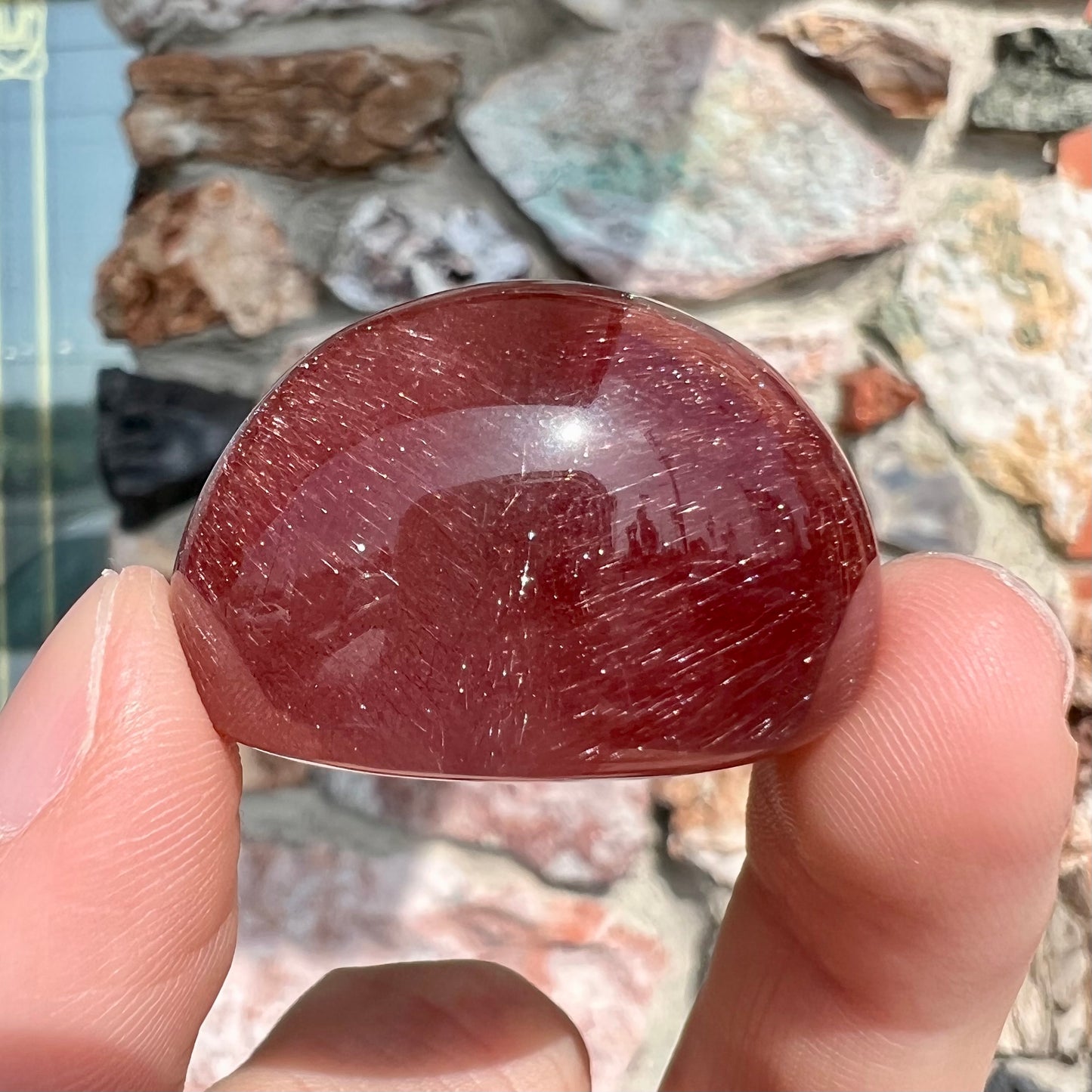 A large, oval cabochon cut strawberry quartz. The stone has a trapiche star-like pattern.